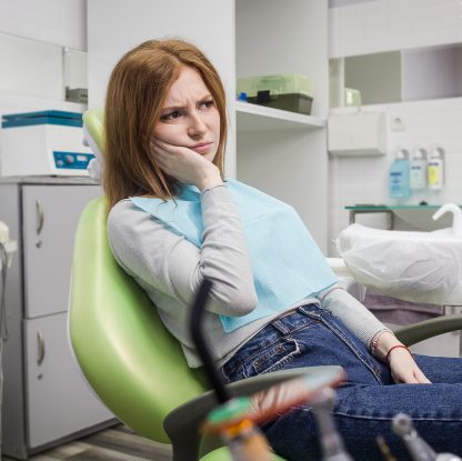 Kobieta na fotelu dentystycznym z bólem zęba