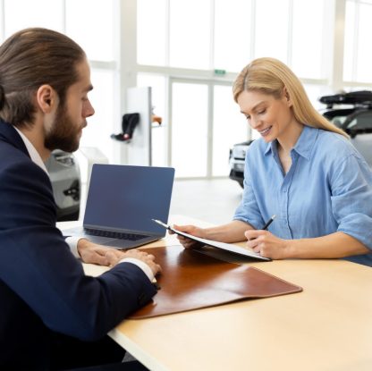 kobieta podpisująca umowę w salonie samochodowym